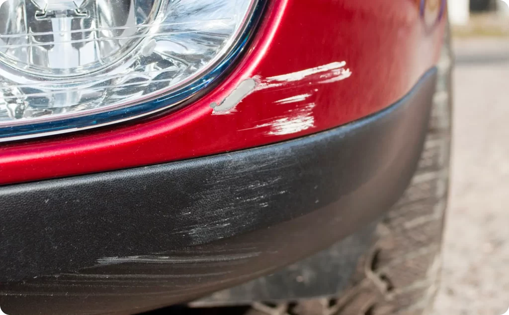 a scratched red car bumper - weR1 automotive